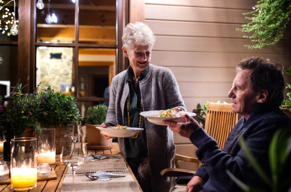 Portrait of happy senior couple having dinner in the evening on terrace.