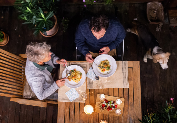 Top view of senior couple in wheelchair having dinner in the evening on terrace, relaxing.