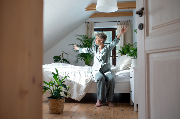 Happy senior woman in bed at home getting up in the morning.