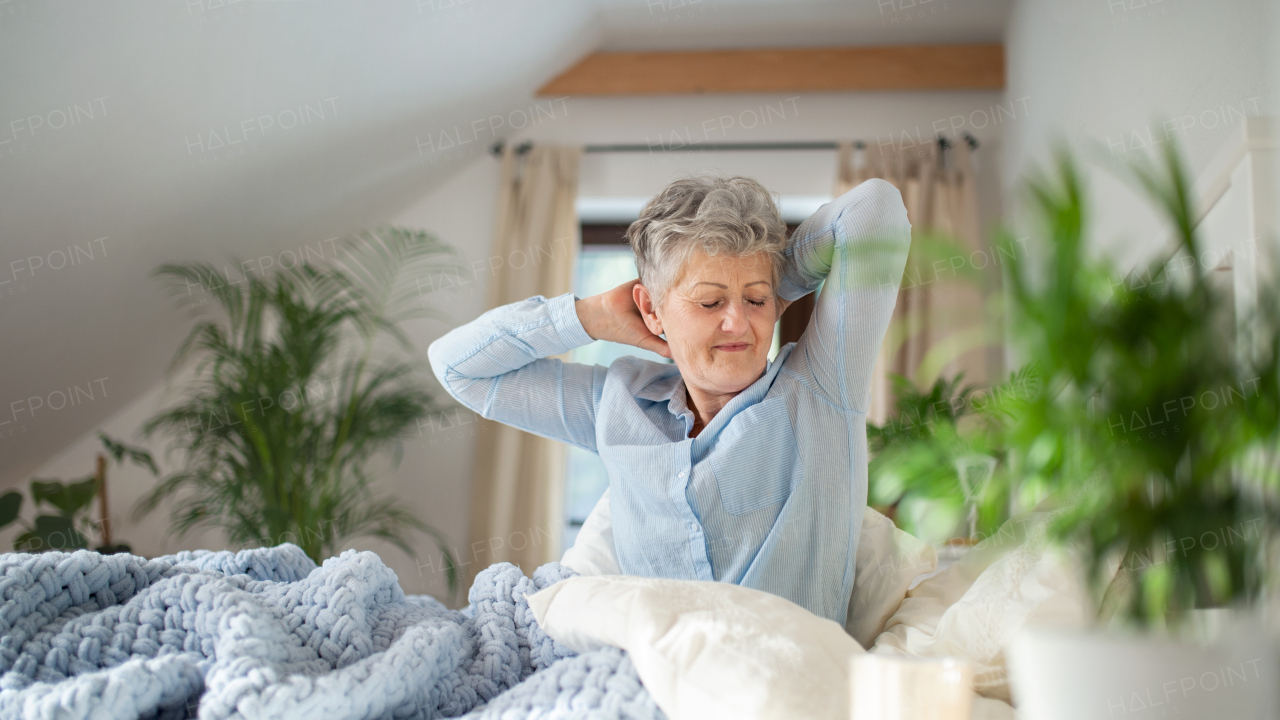 Happy senior woman in bed at home getting up in the morning.