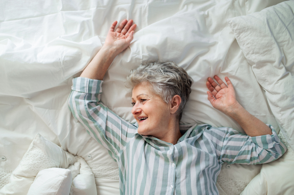 A top view of happy senior woman in bed at home, relaxing.