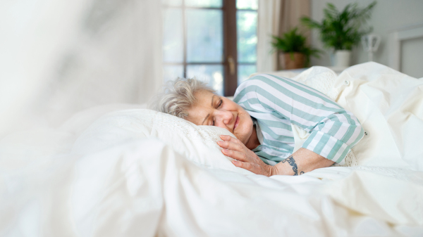 A happy senior woman in bed at home, sleeping.