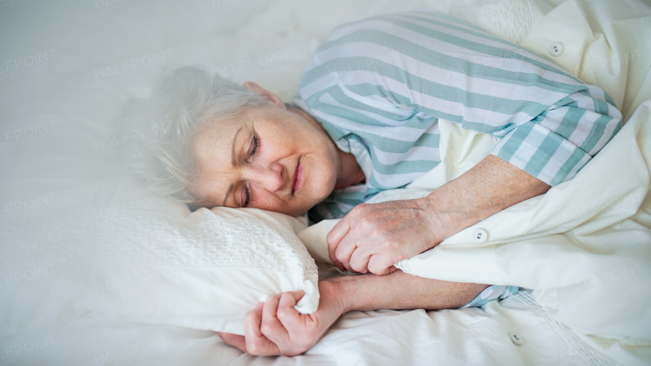 A happy senior woman in bed at home, sleeping.