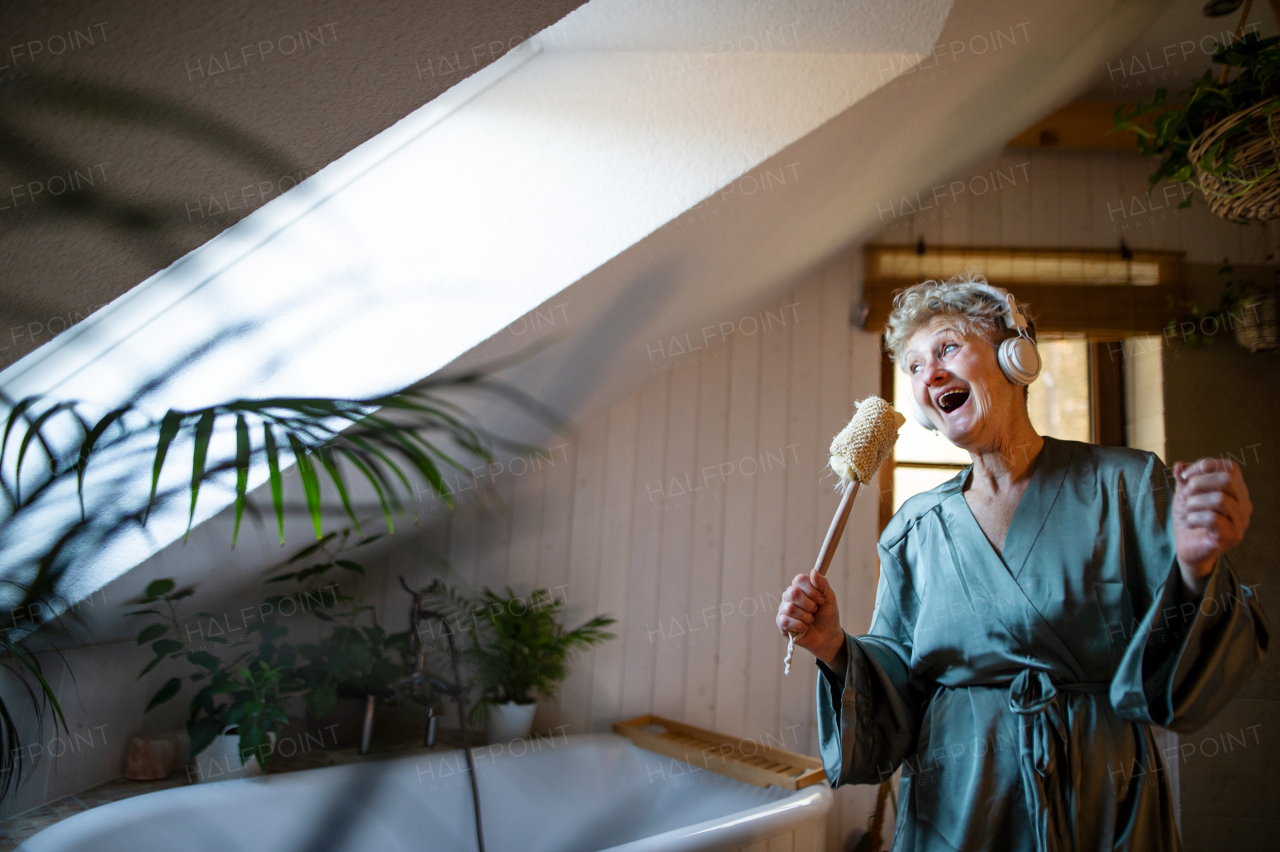 A happy senior woman with headphones singing at home, relax and self-care concept.