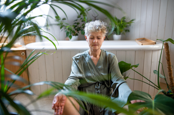 Portrait of senior woman doing yoga in bathroom at home, relax and self-care concept.