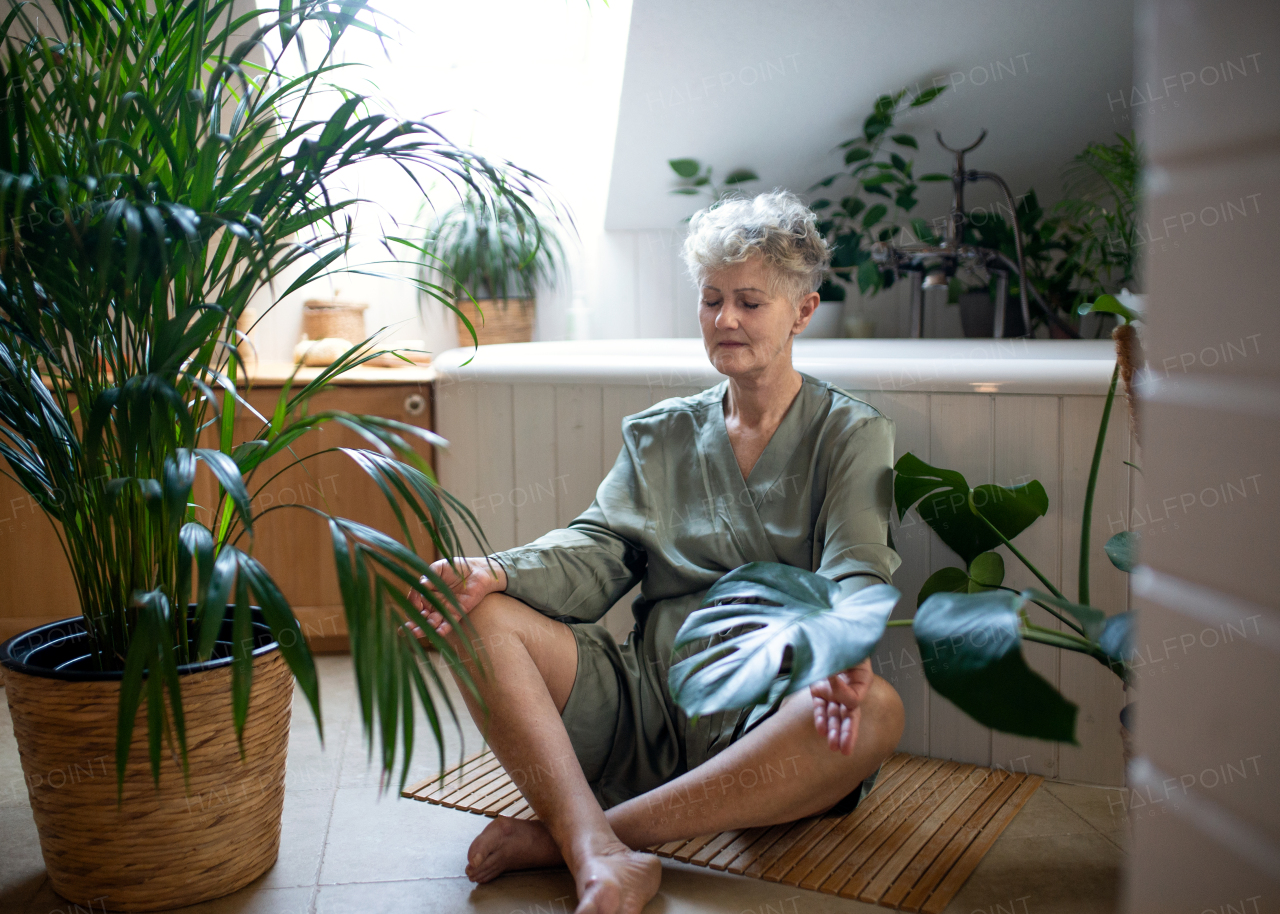 Portrait of senior woman doing yoga in bathroom at home, relax and self-care concept.