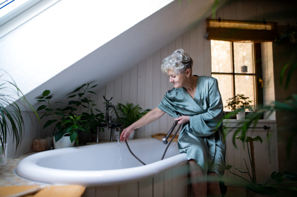 A top view of senior woman in bathroom preparing for a bath at home.