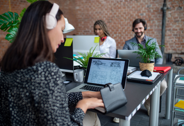 Young and old architects sitting and working at desk in a office, cooperation and coworking concept.