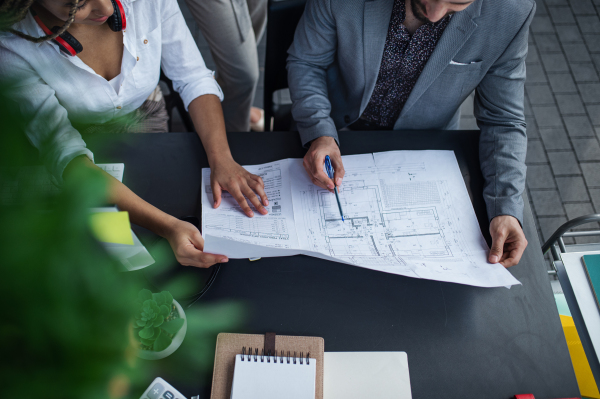 A top view of unrecognizable architects sitting and working at desk in office, cooperation concept.