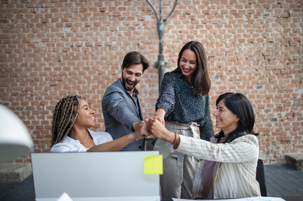 Cheerful young and old businesspeople celebrating success in a office, cooperation concept.