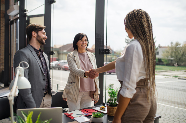 A young woman having job interview and shaking hands in office, business and career concept.