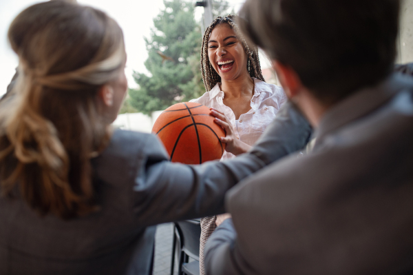 A group of cheerful young businesspeople playing basketball in office, taking a break concept.