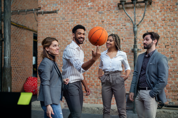 A group of cheerful young businesspeople playing basketball in office, teambuilding concept.