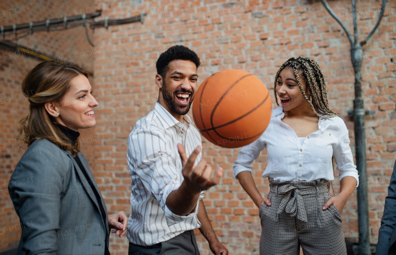 A group of cheerful young businesspeople playing basketball in office, taking a break concept.