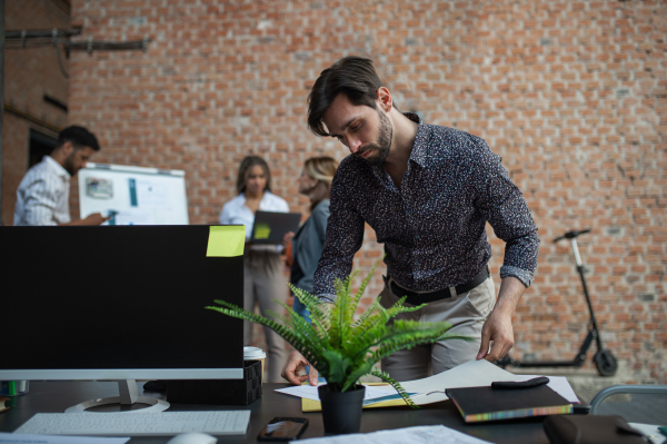 A young businessman standing and working in office, cooperation, presentation and brainstorming concept.