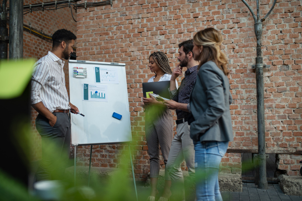 Cheerful young businesspeople standing and working in office, a cooperation and brainstorming concept.