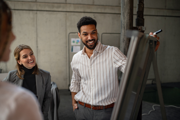 Cheerful young businesspeople standing and working in office, a cooperation and brainstorming concept.