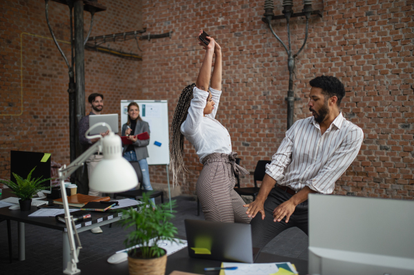 Cheerful young businesspeople having fun in office, a cooperation and brainstorming concept.