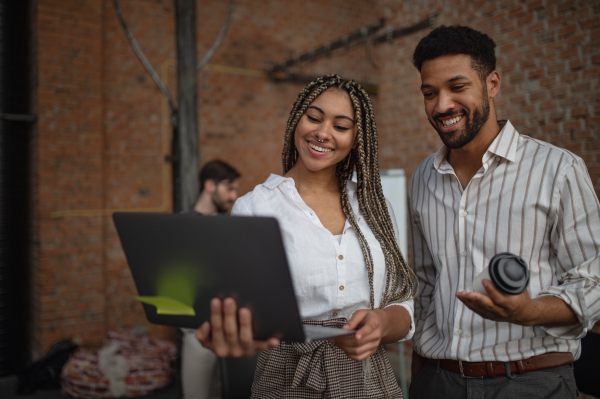 Cheerful young businesspeople with tablet working in office, a cooperation concept.