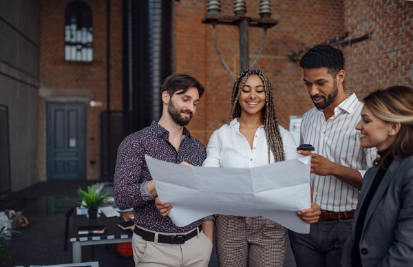 Cheerful young businesspeople standing and working in office, a cooperation and brainstorming concept.