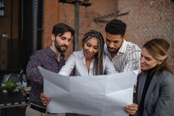 Cheerful young businesspeople standing and working in office, a cooperation and brainstorming concept.