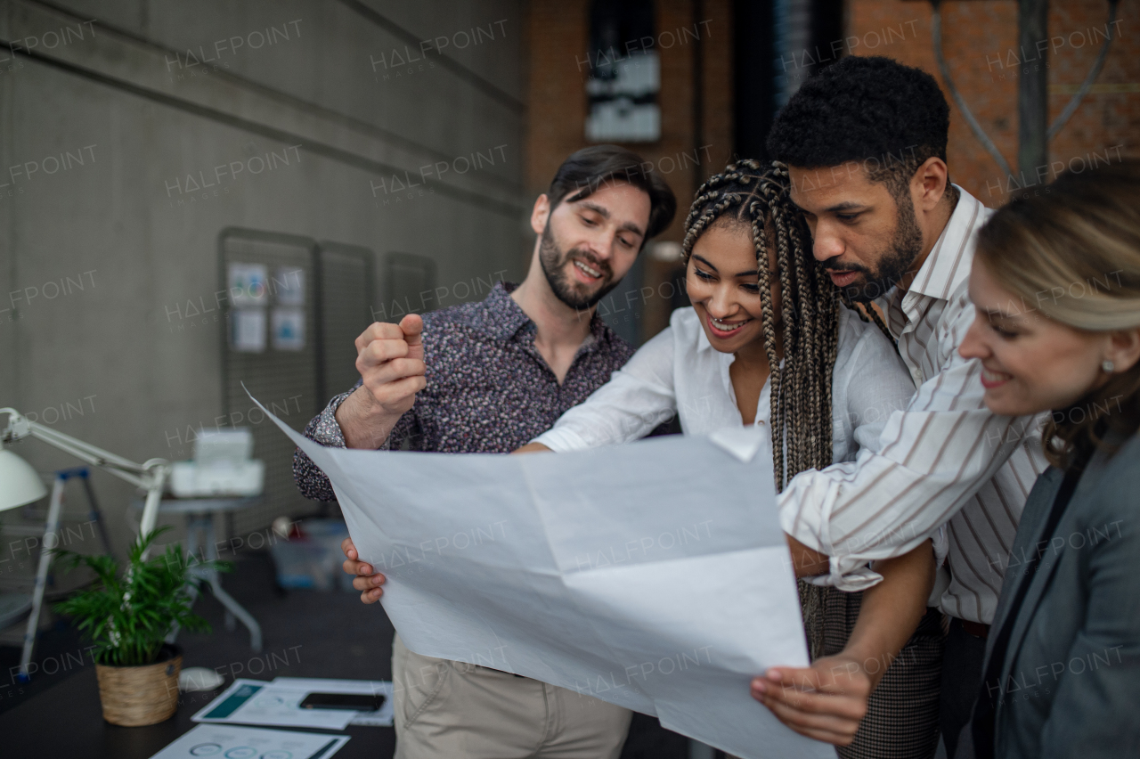 Cheerful young businesspeople standing and working in an office, cooperation concept.