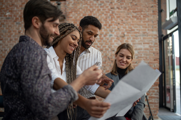 Cheerful young businesspeople standing and working in office, a cooperation and brainstorming concept.