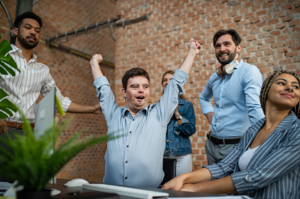 A happy down syndrome man with businesspeople in office, social inclusion and cooperation concept.