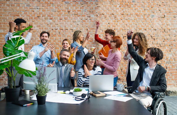 A group of excited entrepreneurs working on project indoors in office, celebrating successful contract.