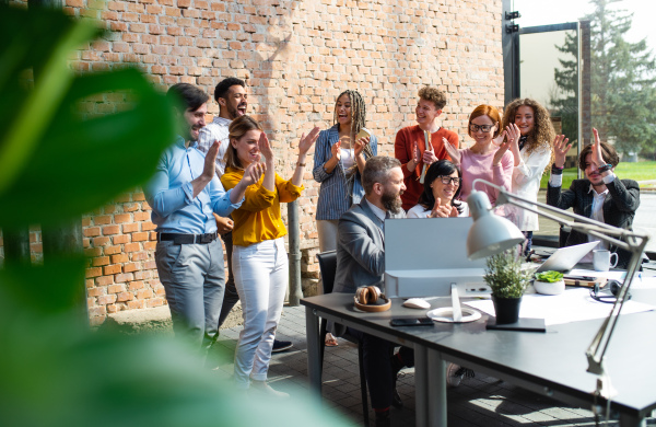 A group of excited entrepreneurs working on project indoors in office, celebrating successful contract.