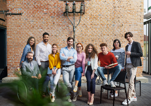 Portrait of group of entrepreneurs looking at camera indoors in office, inclusion of disabled ceoncept.