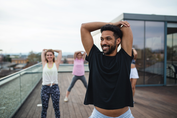 A group of young people doing exercise outdoors on terrace, sport and healthy lifestyle concept.