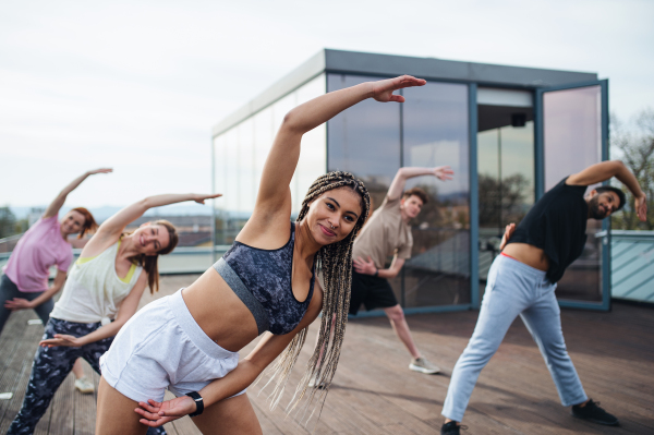 A group of young people doing exercise outdoors on terrace, sport and healthy lifestyle concept.