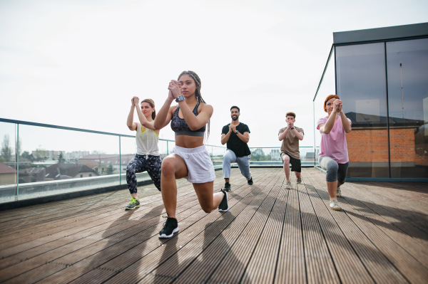 A group of young people doing exercise outdoors on terrace, sport and healthy lifestyle concept.