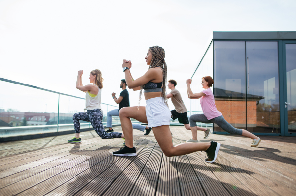 A group of young people doing exercise outdoors on terrace, sport and healthy lifestyle concept.