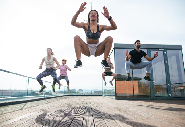 A group of young people doing exercise outdoors on terrace, sport and healthy lifestyle concept.