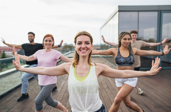 A group of young people doing exercise outdoors on terrace, sport and healthy lifestyle concept.