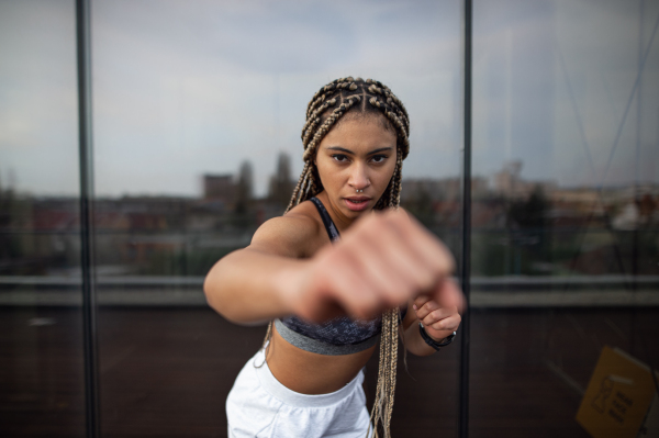 A young woman doing exercise and looking at camera outdoors on terrace, sport and healthy lifestyle concept.