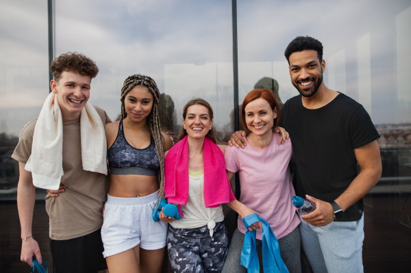 A group of young people standing after exercise outdoors on terrace, sport and healthy lifestyle concept.