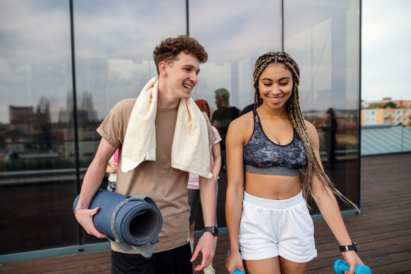 A young couple talking after exercise outdoors on terrace, sport and healthy lifestyle concept.