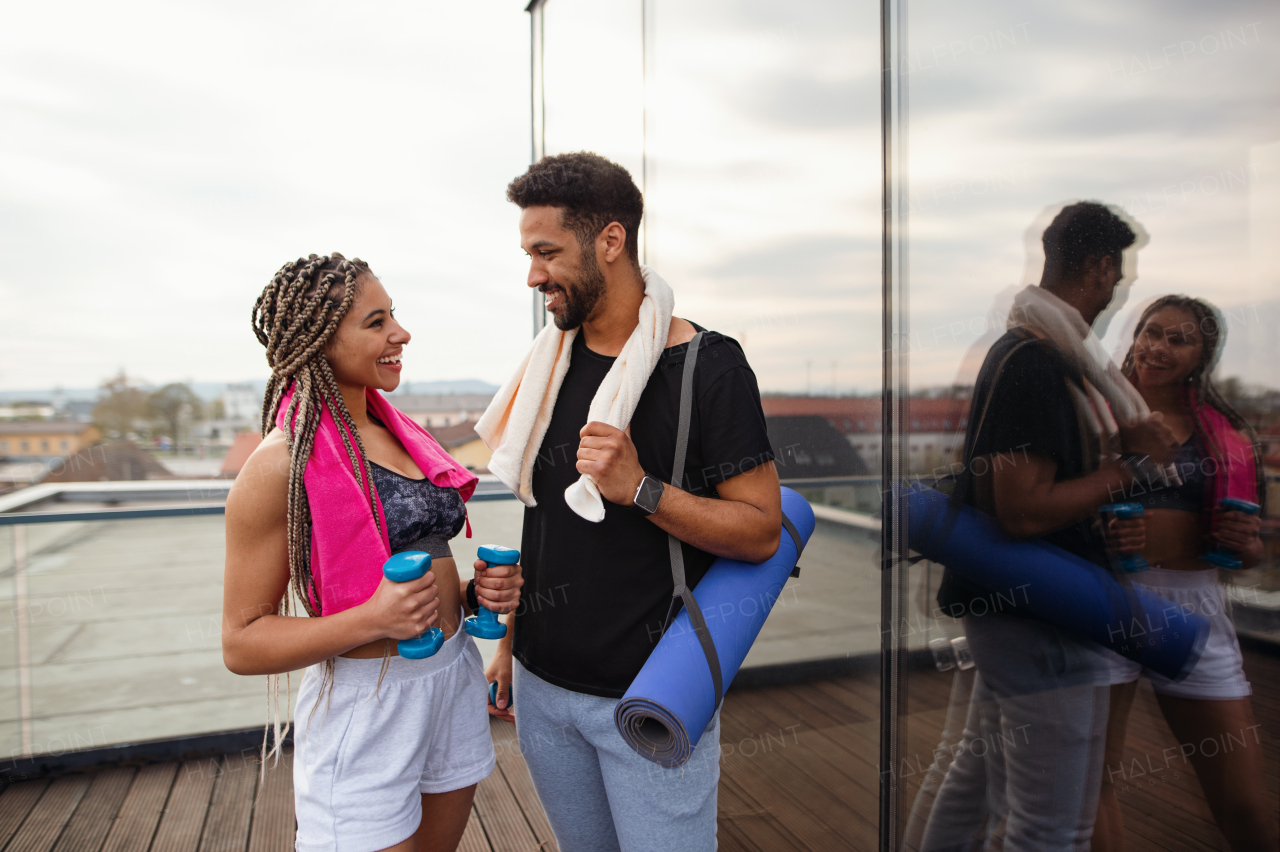 A young couple talking after exercise outdoors on terrace, sport and healthy lifestyle concept.