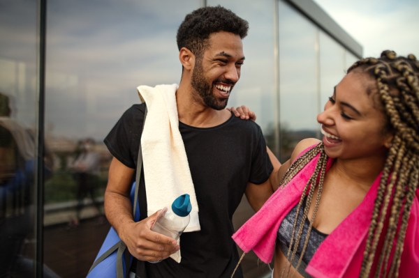 A young couple talking after exercise outdoors on terrace, sport and healthy lifestyle concept.