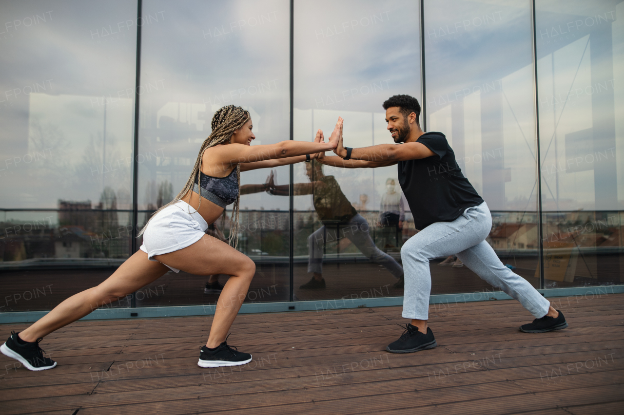 A young couple doing plank exercise workout outdoors on terrace, sport and healthy lifestyle concept.