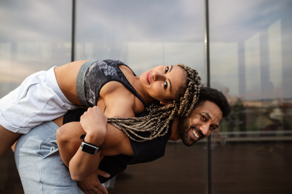 A young couple having fun after exercise outdoors on terrace, sport and healthy lifestyle concept.