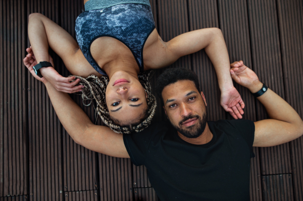 A top view of young couple looking at camera after exercise outdoors on terrace, sport and healthy lifestyle concept.