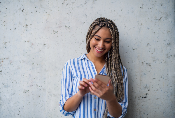 A portrait of woman freelancer standing indoors, using smarpthone.