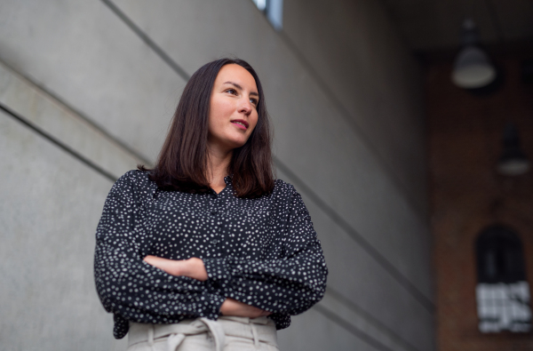 A low-angle view portrait of mid adult businesswoman standing indoors, arms crossed.