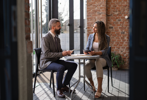 A portrait of businesspeople sitting at the table and working indoors, discussing issues.