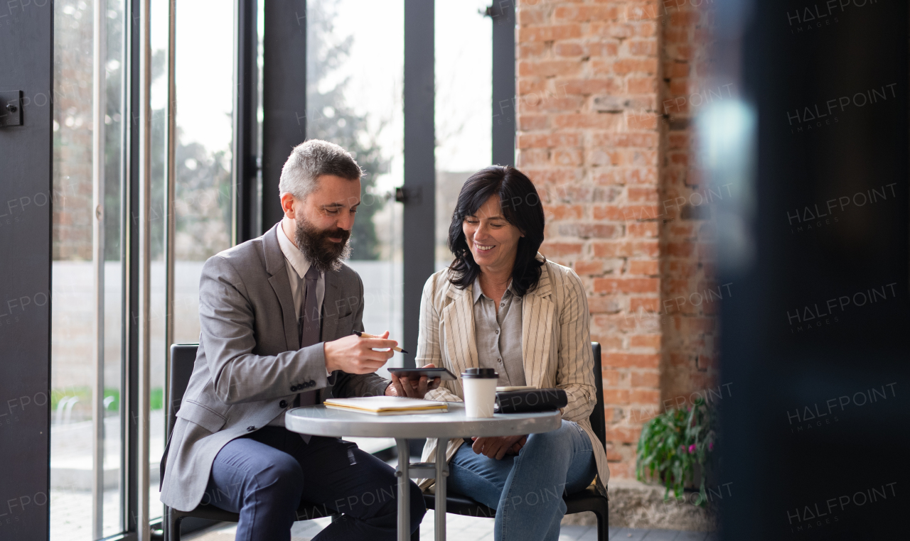 A portrait of businesspeople sitting at the table and working indoors, discussing issues.