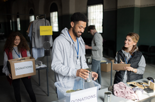 A group of volunteers working in community charity donation center, sorting out clothes and canned food.